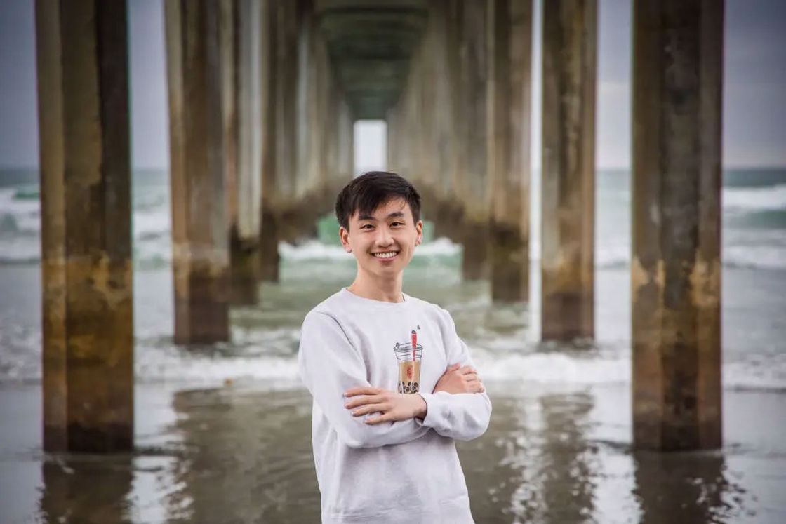 High school boy wearing a gray sweatshirt while posing at a beach