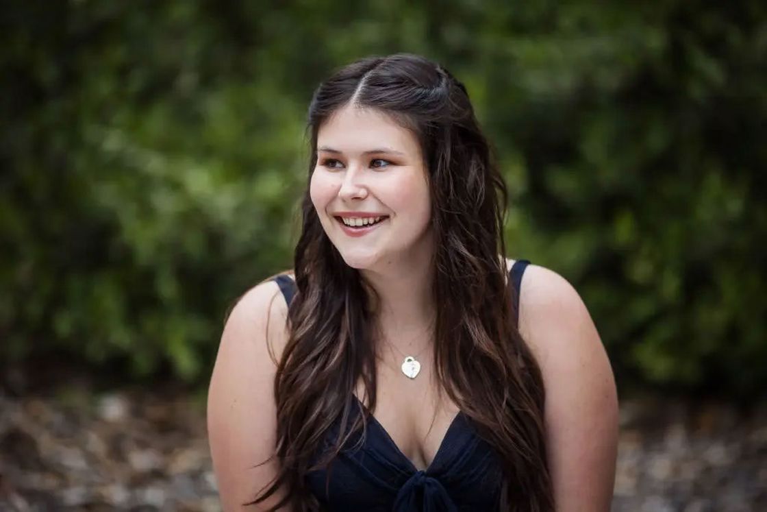 Young woman wearing a blue plunging dress posing outdoors for her senior photo