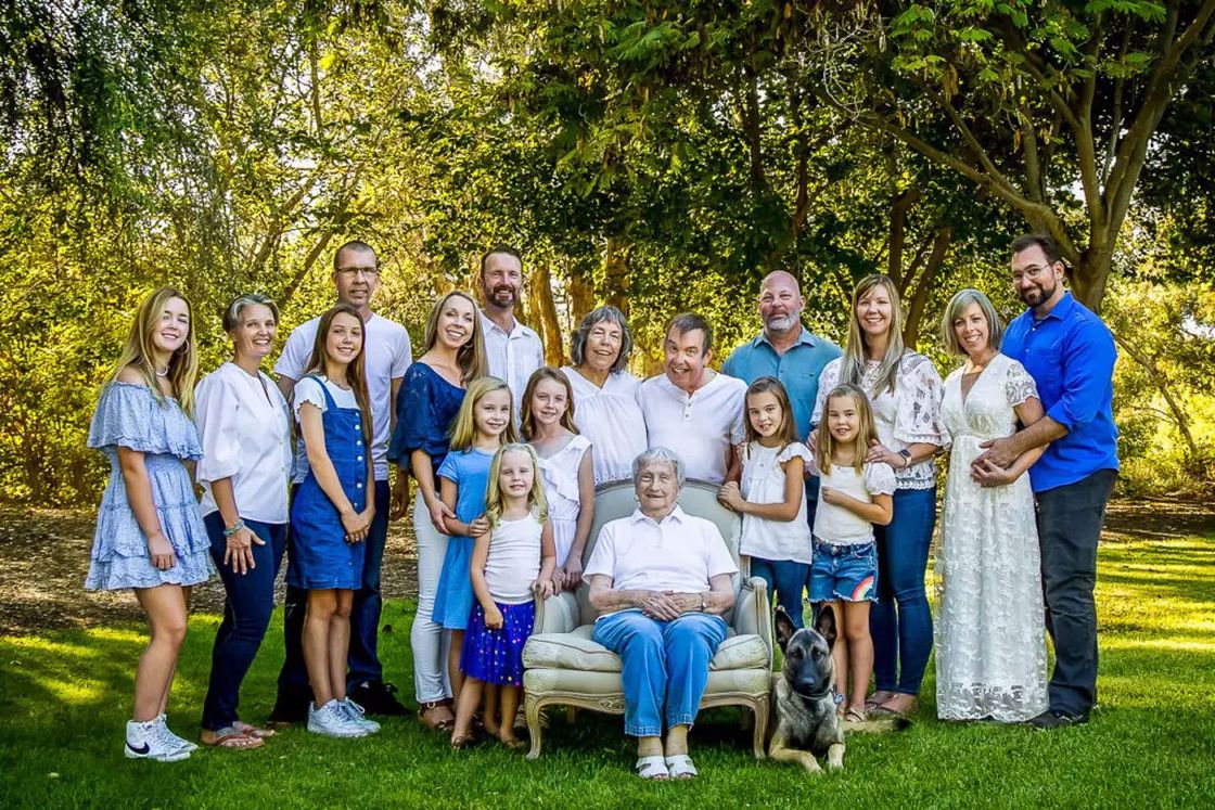 A huge family with their grandmother seated in the middle taking a photo in an outdoor garden