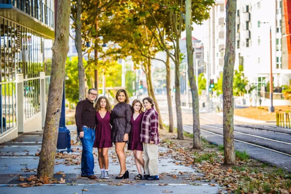 Family of five taking their photo in an empty street with fallen dried leaves