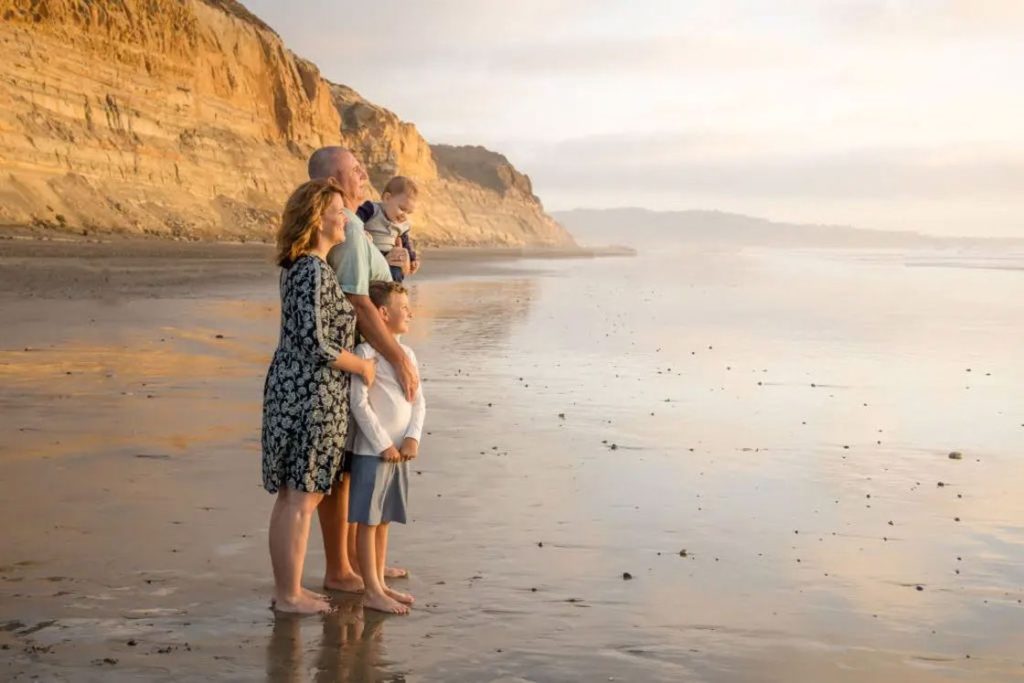 Family of four looking over the sunset while taking their family photo shoot in a beach