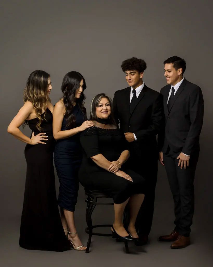 Family of five with their mother sitting at the center posing for their family photoshoot in a studio