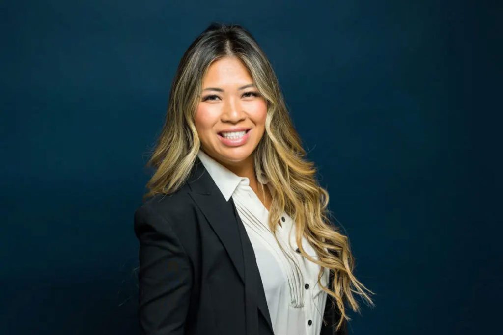 Woman wearing a casual black coat and white inner wear smiling openly for her headshot