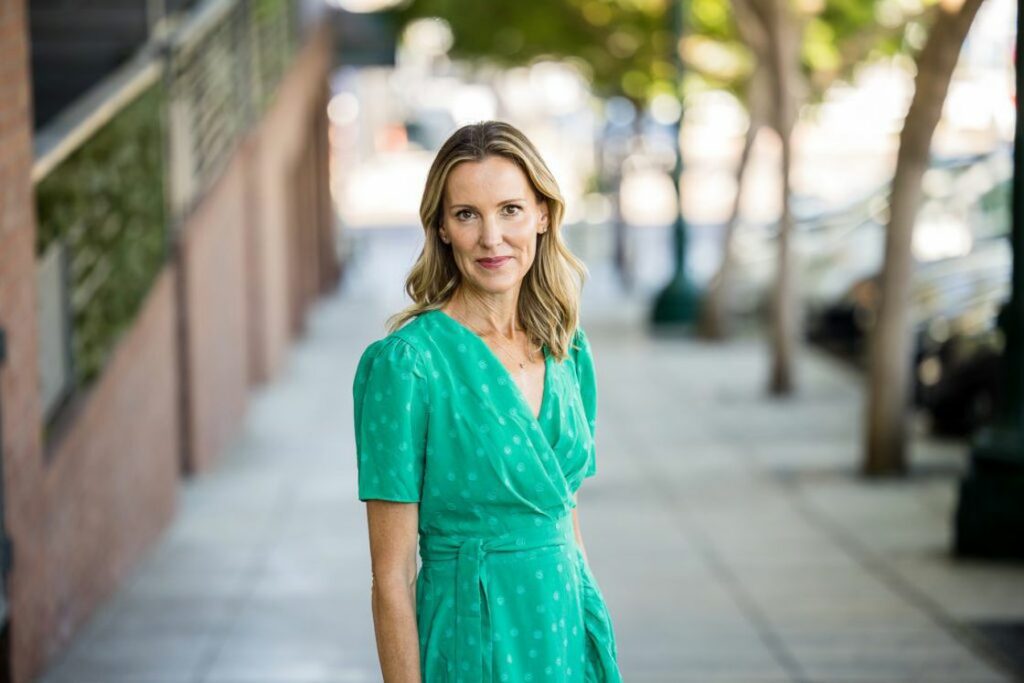 Woman wearing a green wrap dress posing in the middle of a sidewalk for her headshot