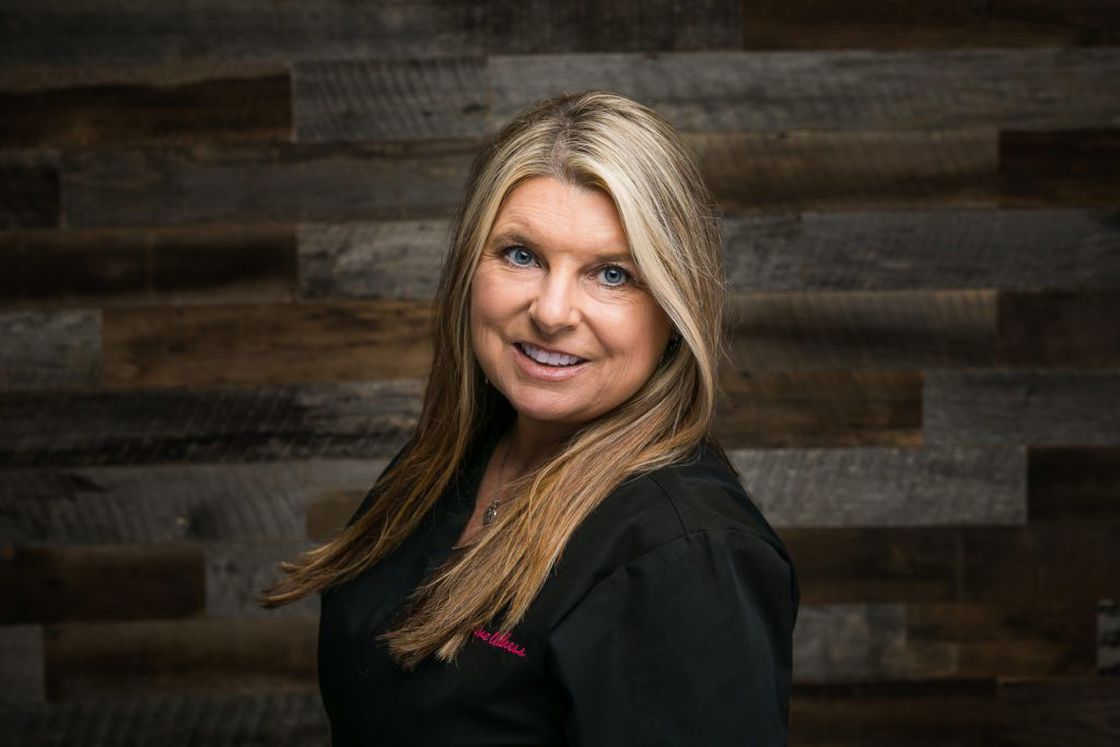 Woman wearing black medical scrubs while posing in a studio for her headshot
