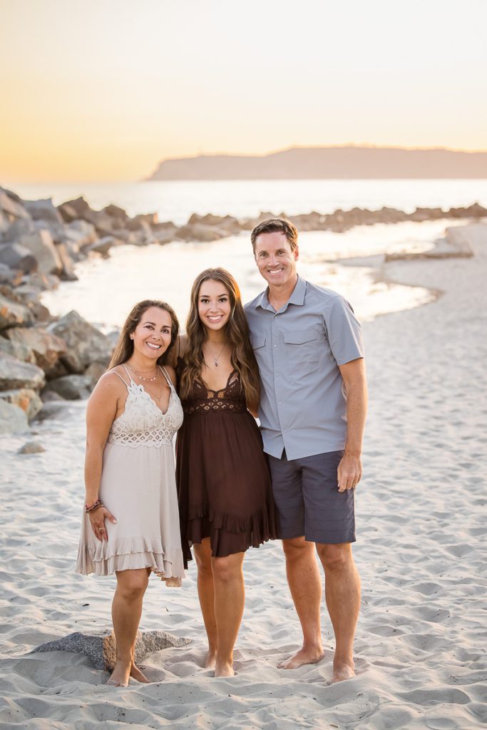 Family of three posing for a family photoshoot in a beach at Coronado