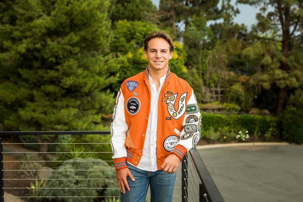 A student with a varsity jacket posing for his senior photograph