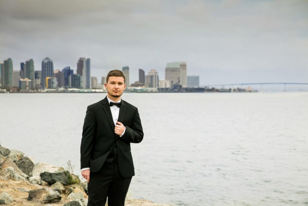 A student outside with his formal suit posing for his graduation photograph