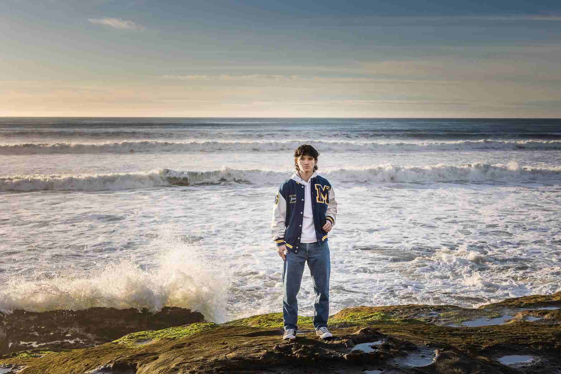 A student posing for his senior portrait on the seashore