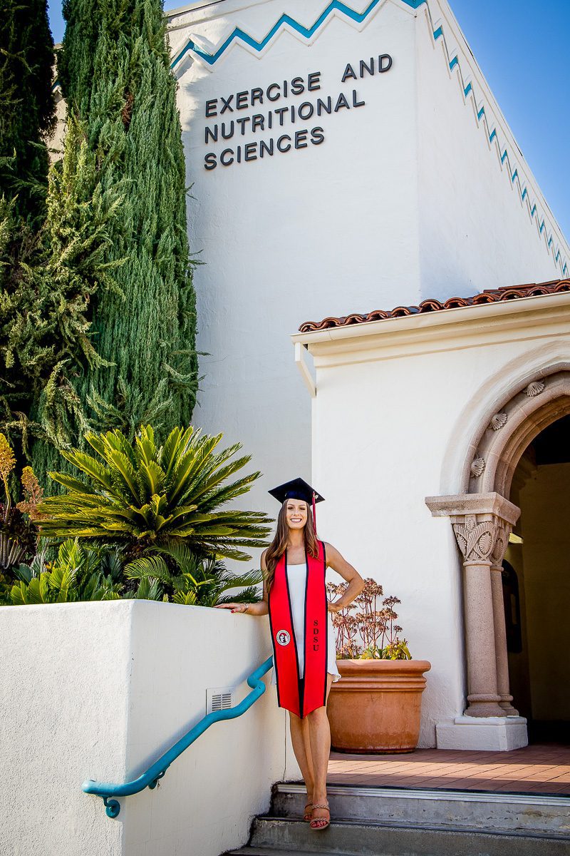 A graduating student with her red sash and graduation cap