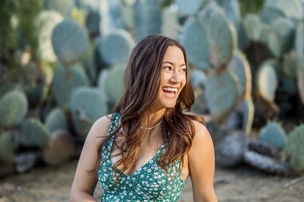 Smiling woman in front of cacti with a floral green dress