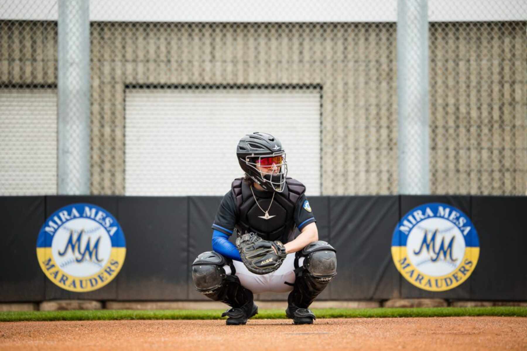 A baseball player in a crouched position, focused on a catcher's mitt in front of him on the field