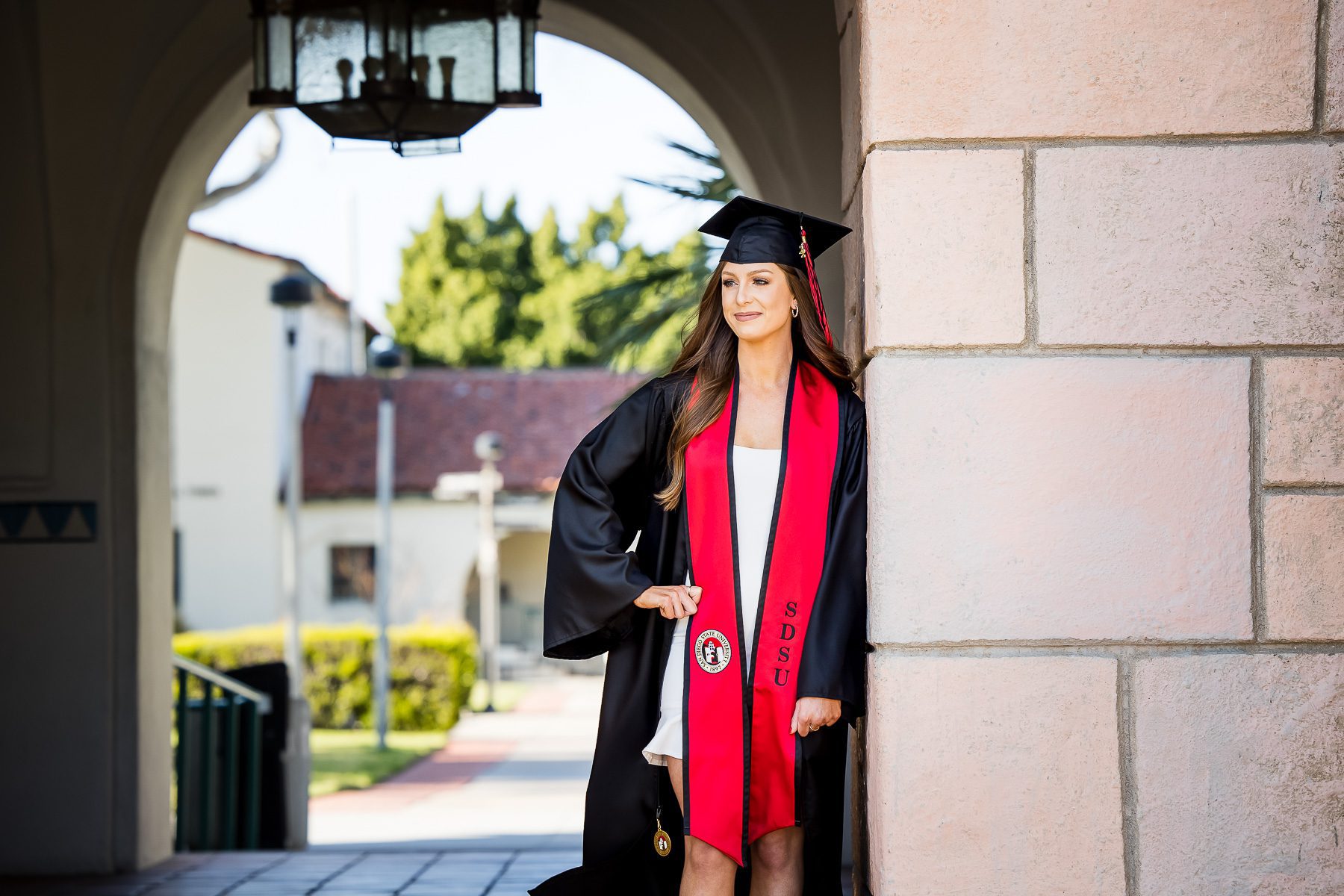 A woman in a graduation gown smiles proudly for a photo